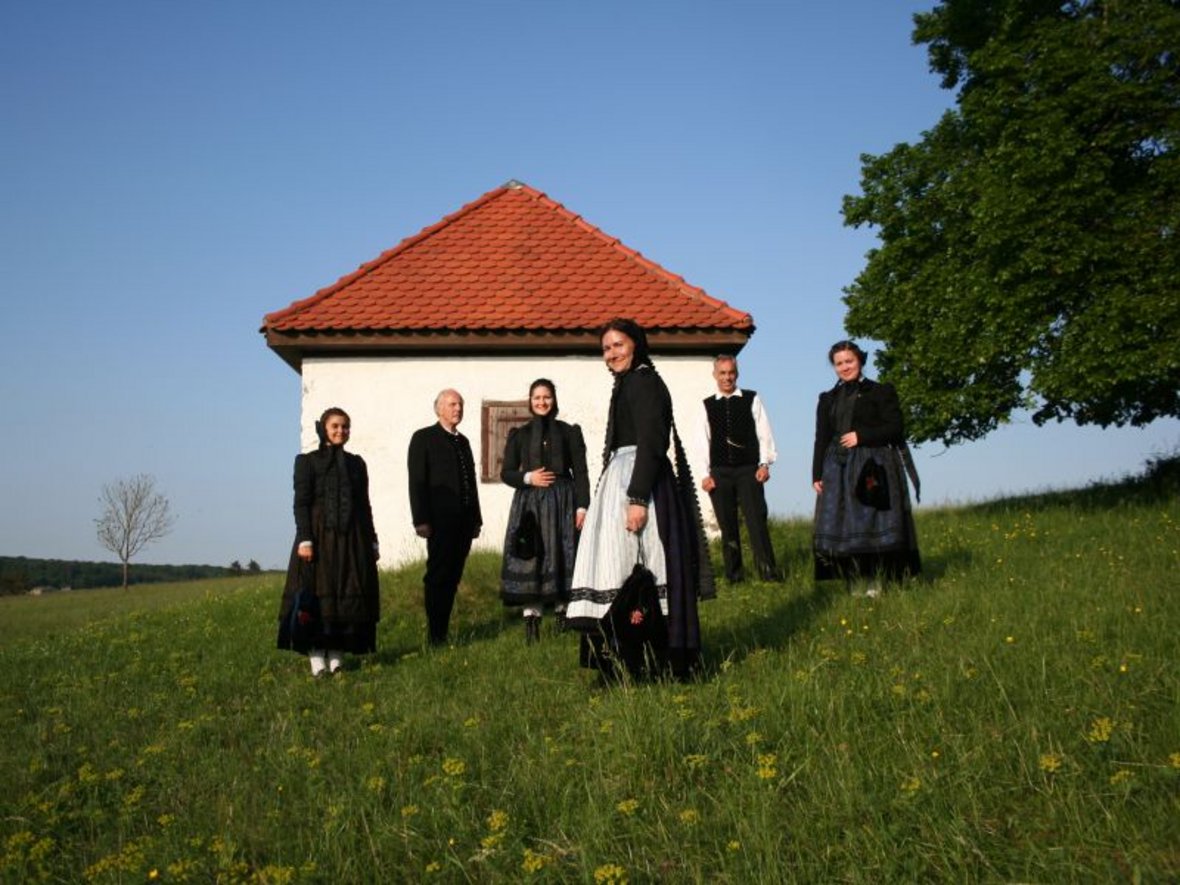 Personen in Trachten vor dem Bleichhäusle