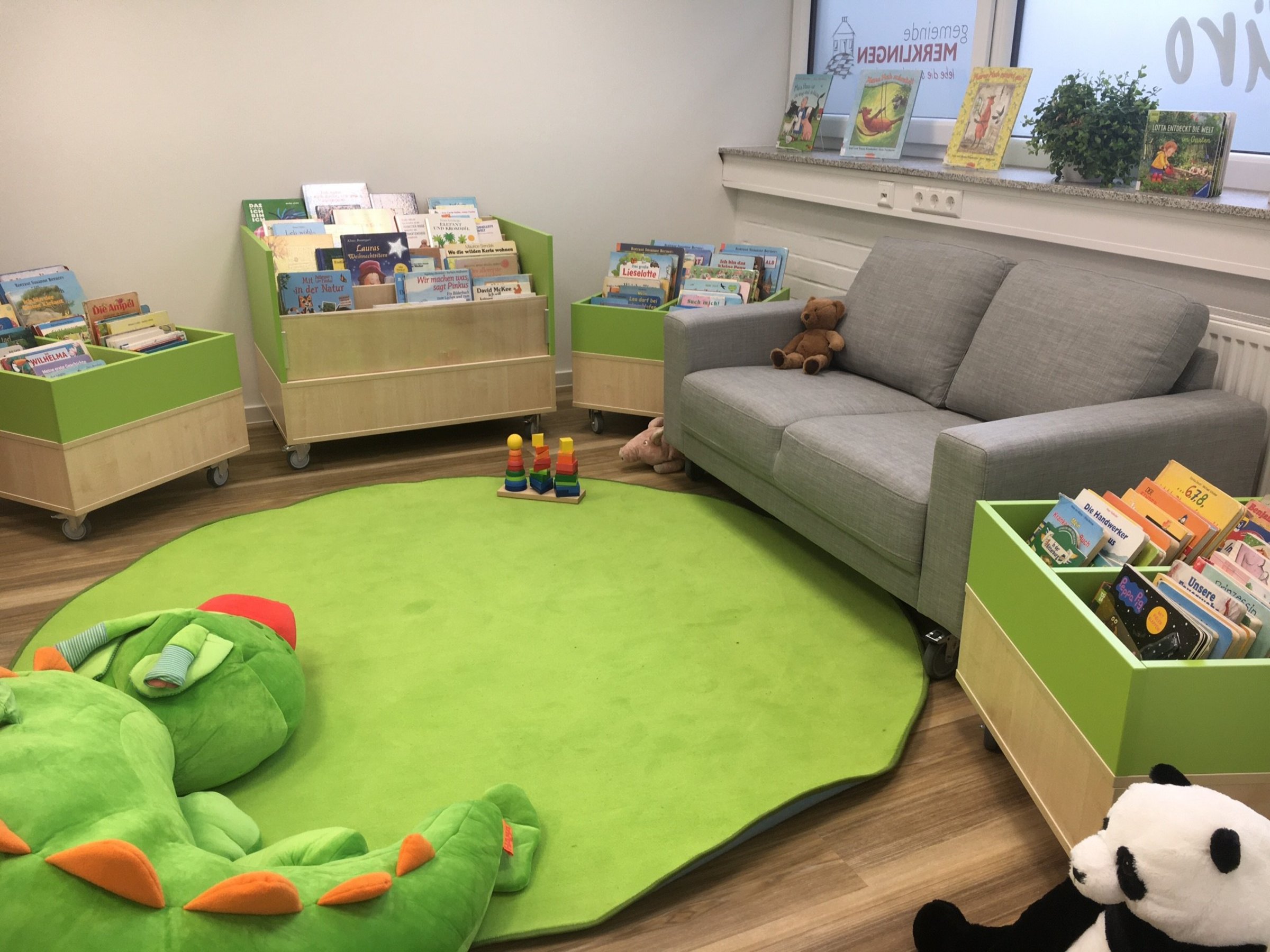 Nebenraum der Bücherei, eingerichtet mit Sofa, Teppich und Kuscheltieren zum gemütlichen Verweilen und Lesen