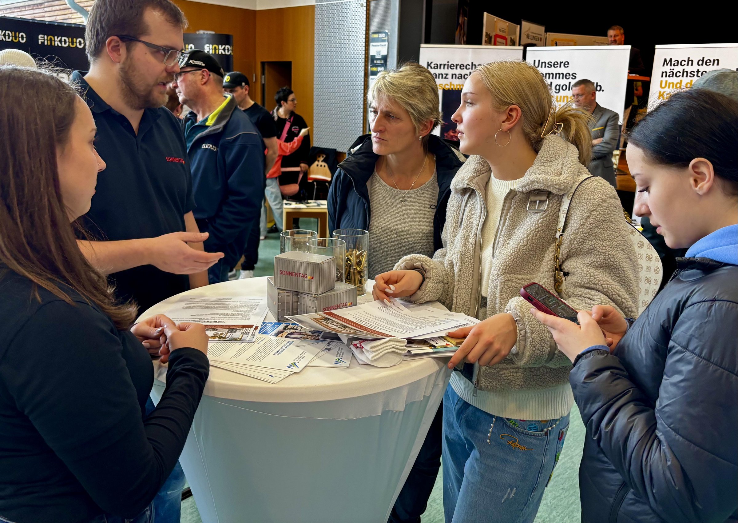 Interessierte Besucher der Messe im Gespräch mit den Vertretern einer Firma